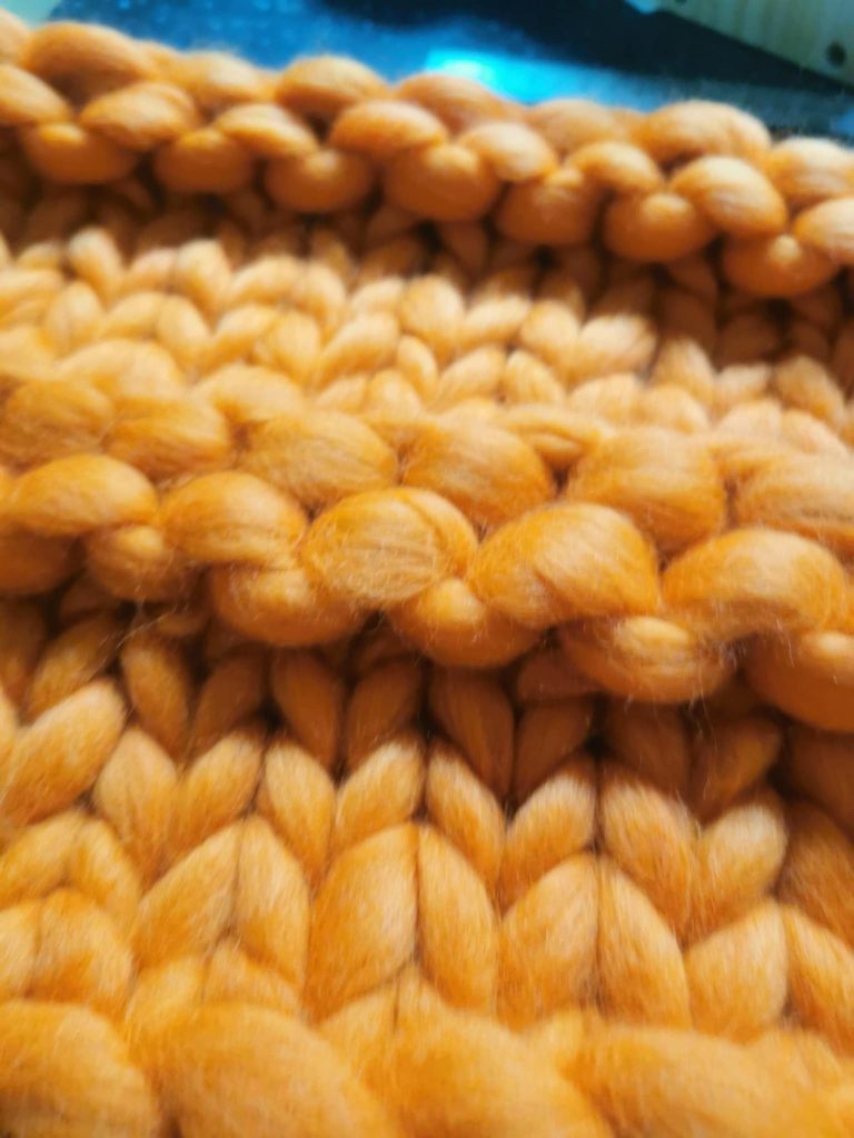 Close-up of textured hand-knit blanket, double-strand detail, using orange merino wool from the Adventures in Wool at Bord Du Lac Artisan.